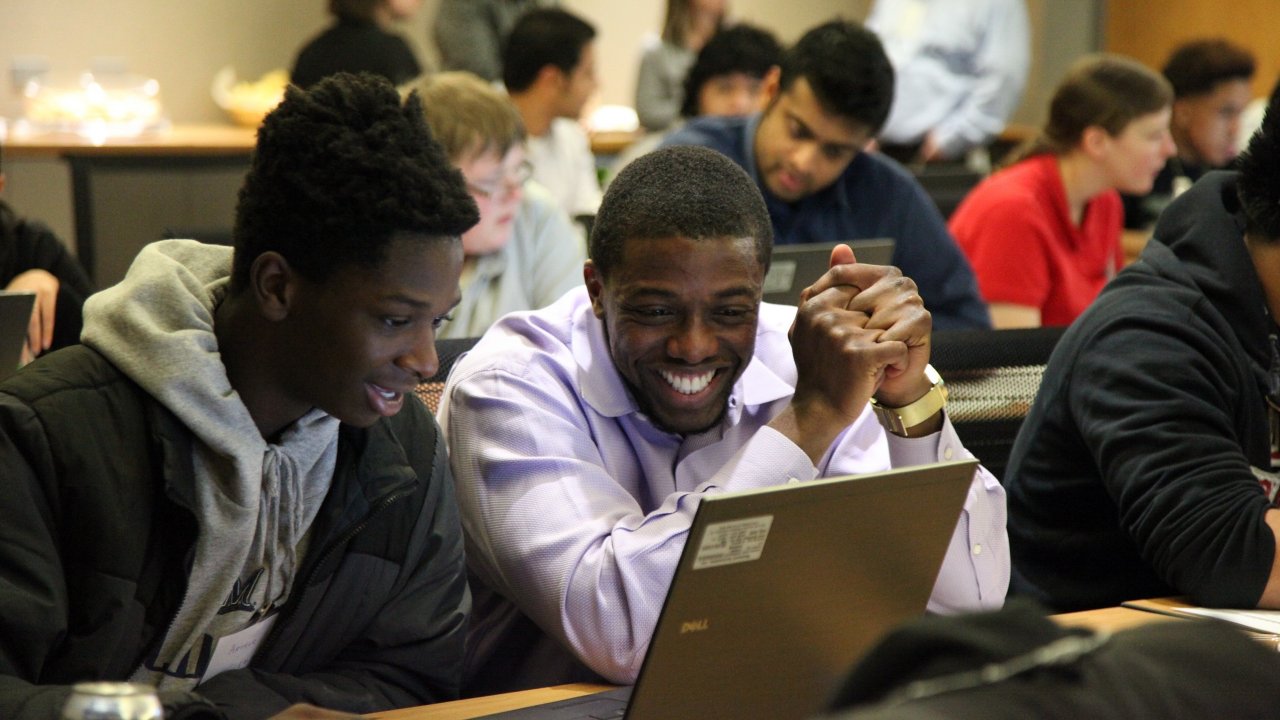Two students looking at laptop smiling.
