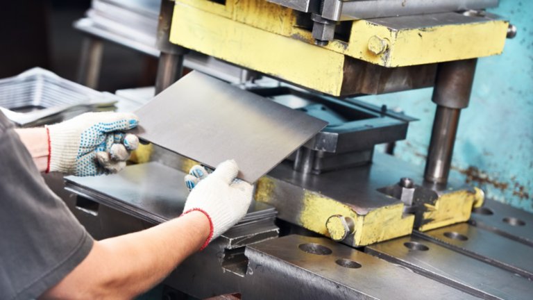 worker at manufacture workshop operating metal press machine