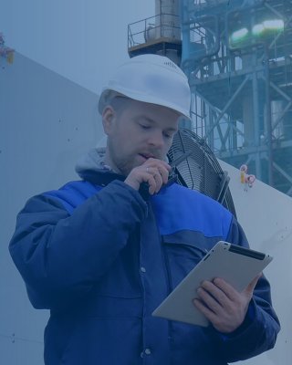 Engineer using digital tablet talking on portable radio standing near industrial air conditioners. Male technician using tablet pc and walkie-talkie outside modern factory