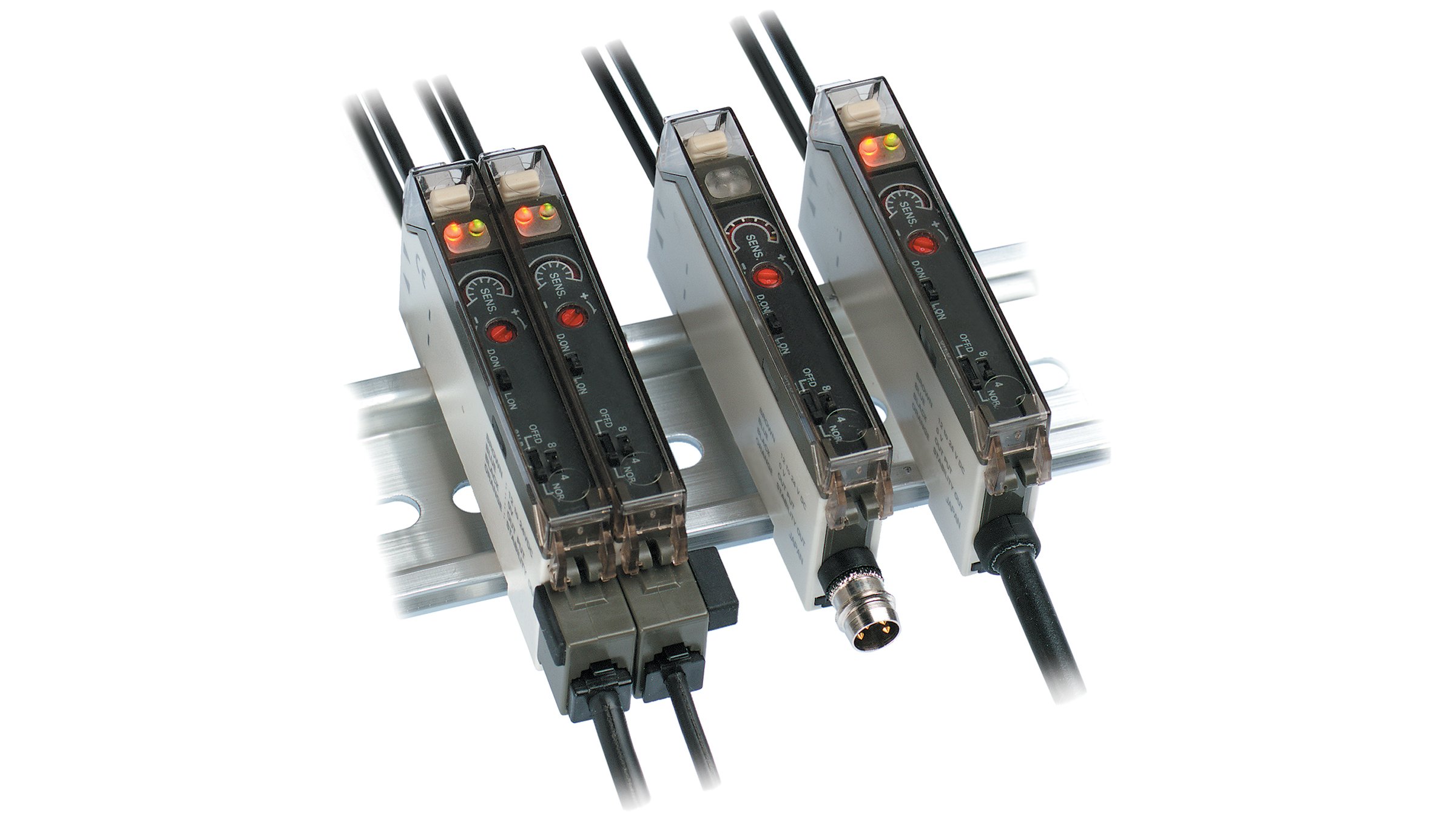 4 détecteurs rectangulaires avec câbles aux extrémités opposées, montés sur un rail DIN