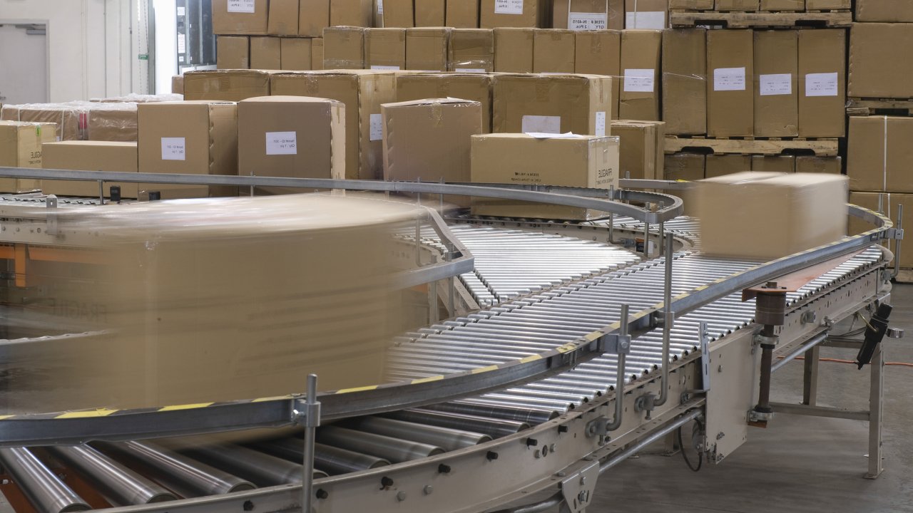 A conveyor belt moves brown boxes through a factory; zero energy state should be established before servicing the equipment for maintenance.