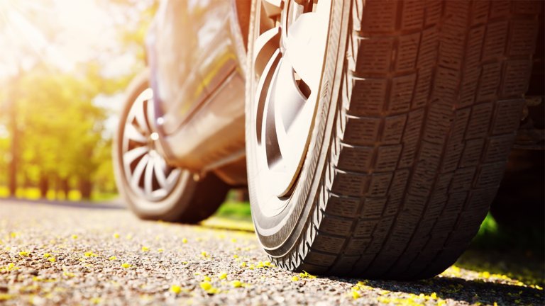 Close-up of car tires on asphalt road on summer day at a park