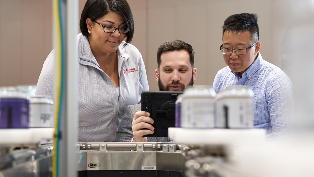 Trois employés de Rockwell Automation regardent un logiciel sur une tablette.