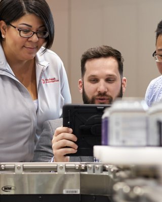 Three Rockwell Automation employees viewing software on a tablet.