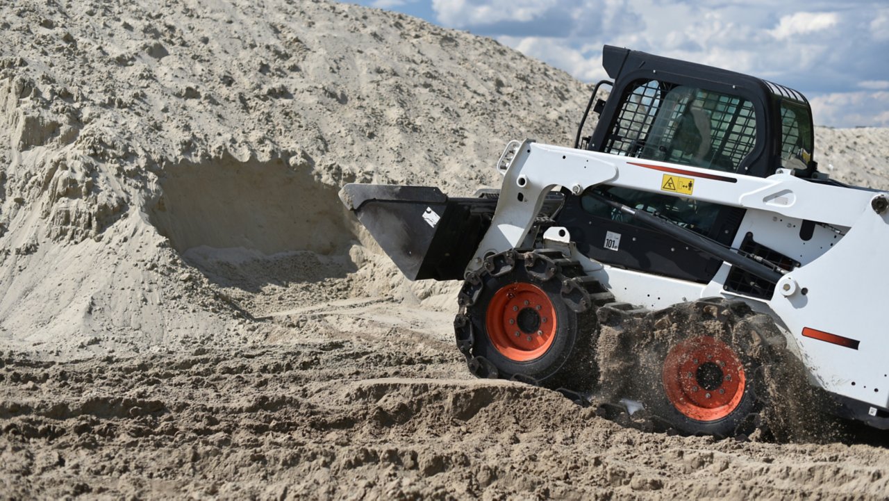 Bobcat pelletant du sable dans un tas sur un site