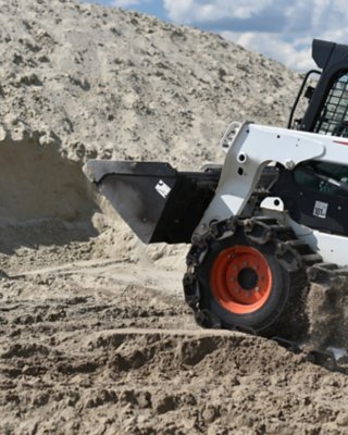 一辆山猫装载机在工地的沙堆中挖沙