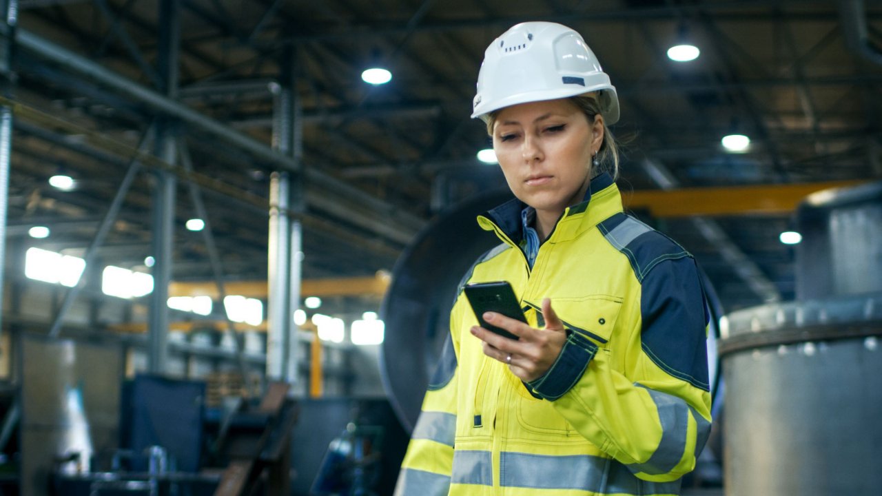 Woman in white hard hat looking at phone