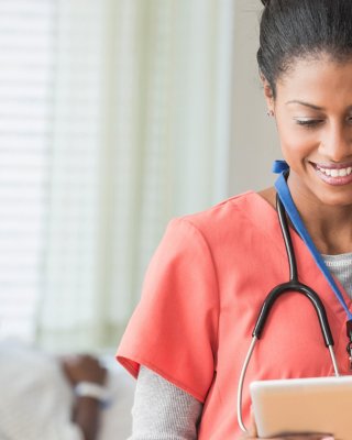 Female care provider wearing scrubs and a stethoscope looking at a tablet