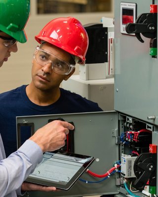 Due operatori dell’assistenza che esaminano un convertitore di frequenza Rockwell Automation.