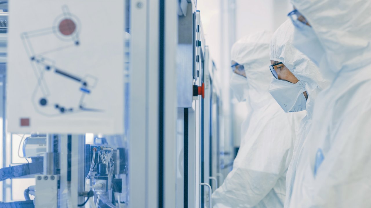 Scientists in sterile clothing using production machines