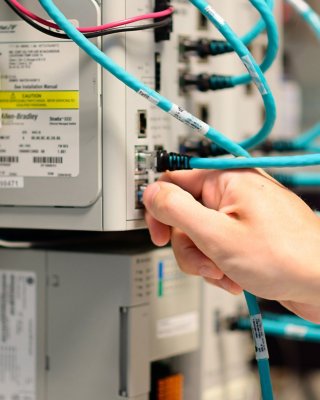 IT Worker's Hand Plugging in Ethernet Cable to Rockwell Automation Stratix Switch