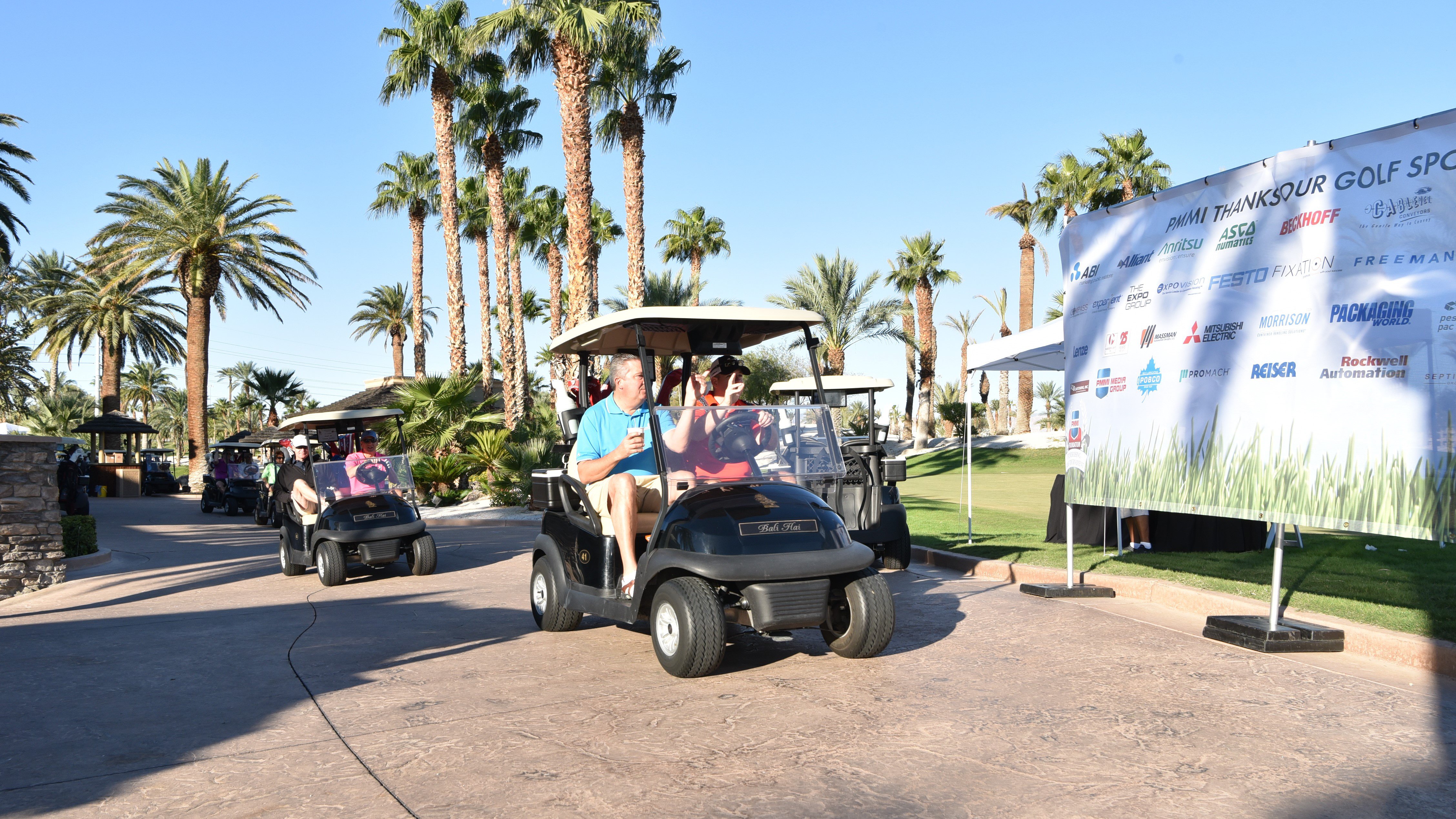 People sitting in golf carts with palm trees in the background