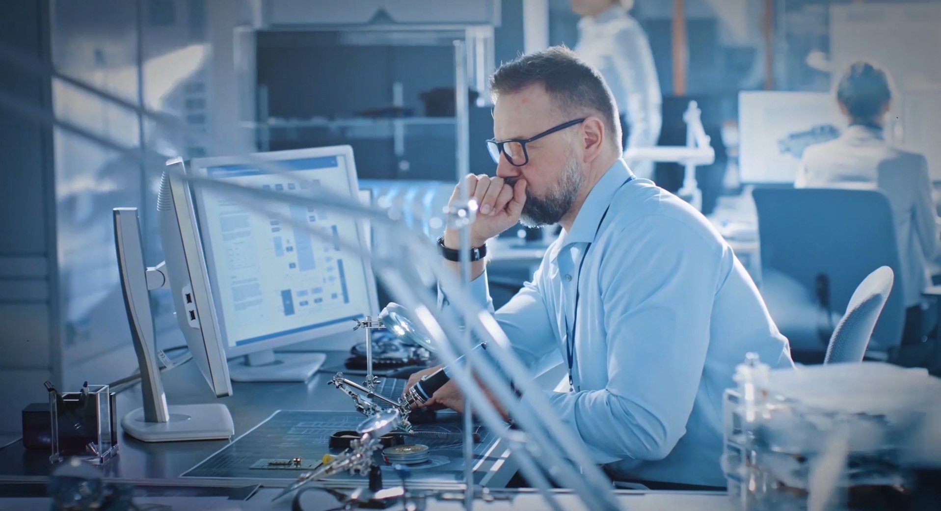 配戴眼鏡的男士在公司的生物科技廠房中，審查監視器上的分析資料。