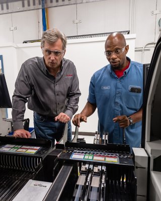 Dois funcionários da Rockwell Automation nas instalações de Twinsburg, em Ohio, olhando para uma máquina em operação