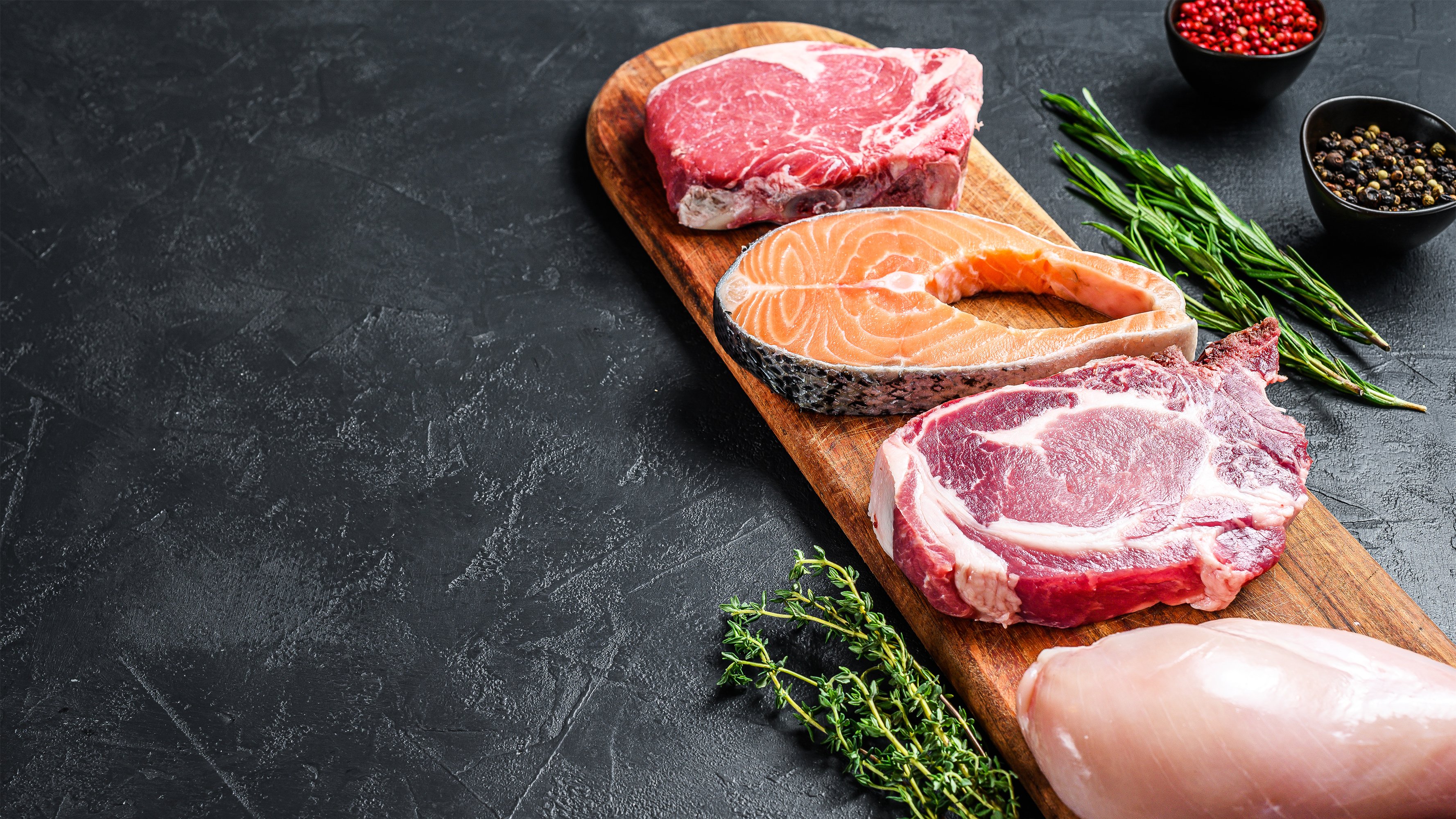 A mix of steaks and meats on a wooden board