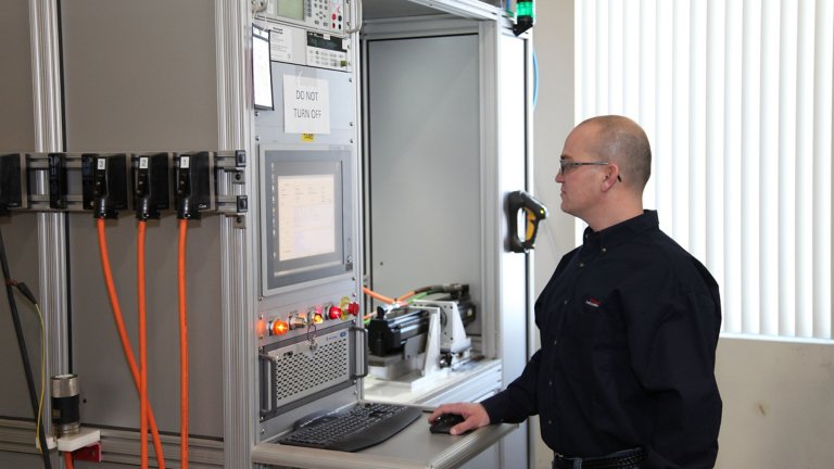 A male technician tests a customer's servo motor being repaired at a Rockwell Automation repair facility.