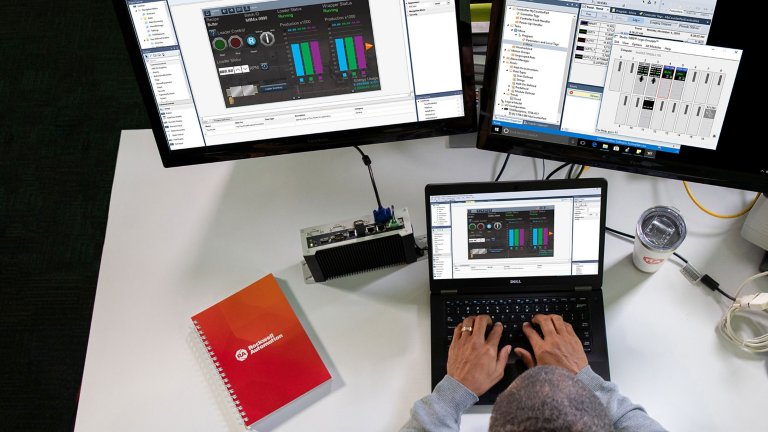 다른 소프트웨어 화면을 표시하는 두 개의 다른 모니터를 두고 노트북의 소프트웨어 응용 프로그램에 정보를 입력하는 남성 직원