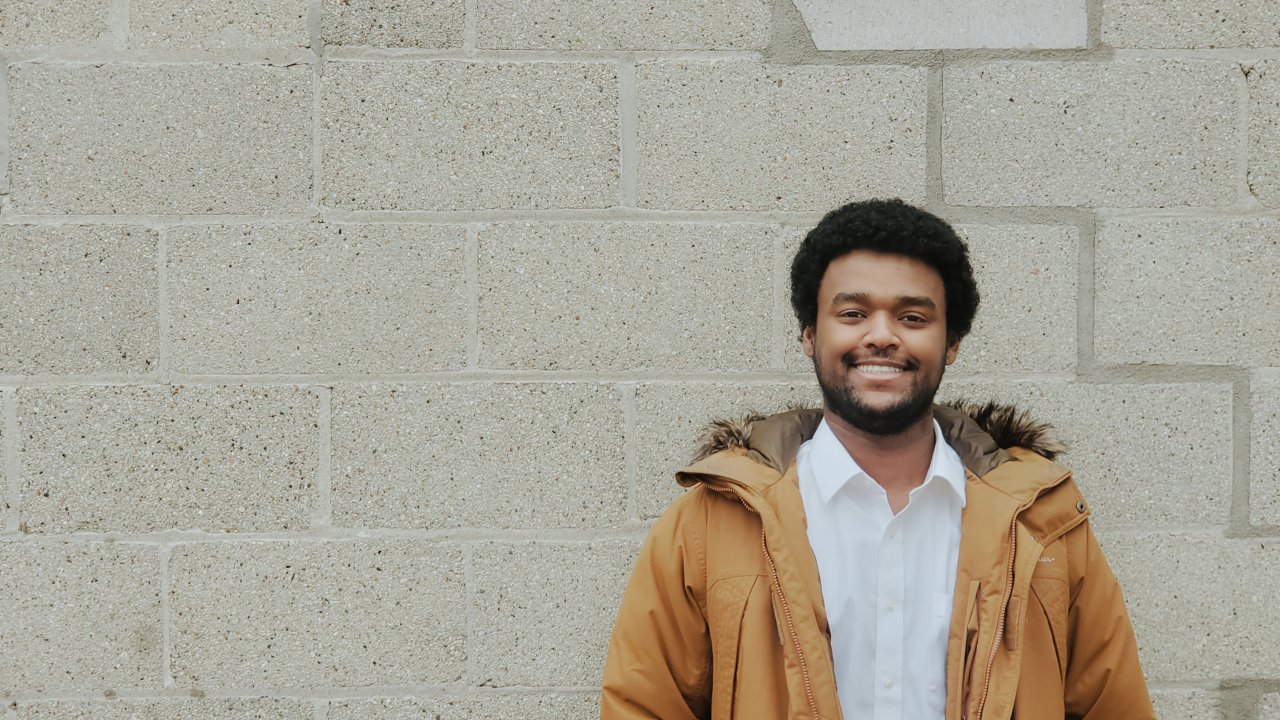 Yonas Habte, leadership development program employee, poses in front of a brick wall.