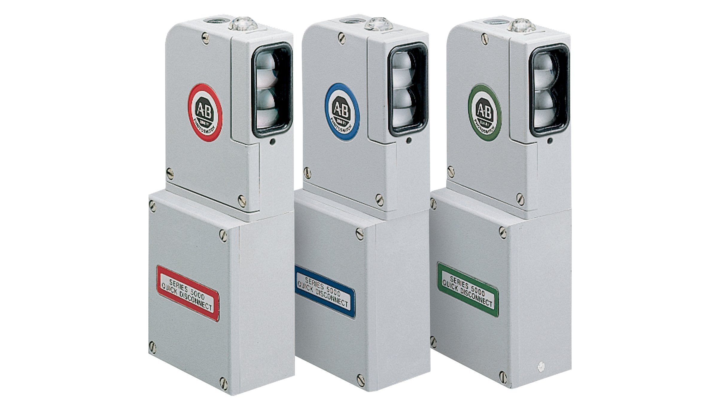 Tres sensores rectangulares grises altos Allen-Bradley con etiquetas rojas, azules y verdes.