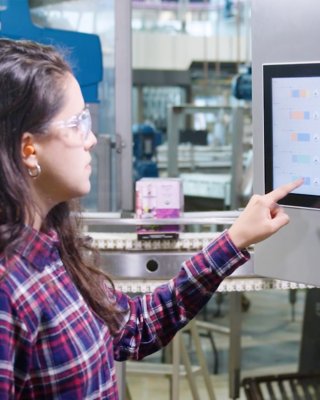 Donna in un ambiente di fabbrica utilizzando un touchscreen ASEM 6300P