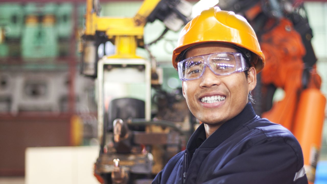 Asian engineer in yellow hard hat and with safety goggles
