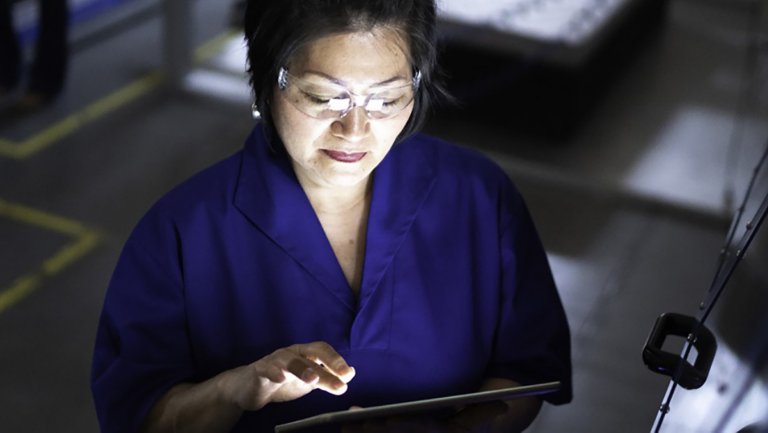 제조 공장에서 보안경을 착용하고 태블릿 PC로 작업을 하는 여성