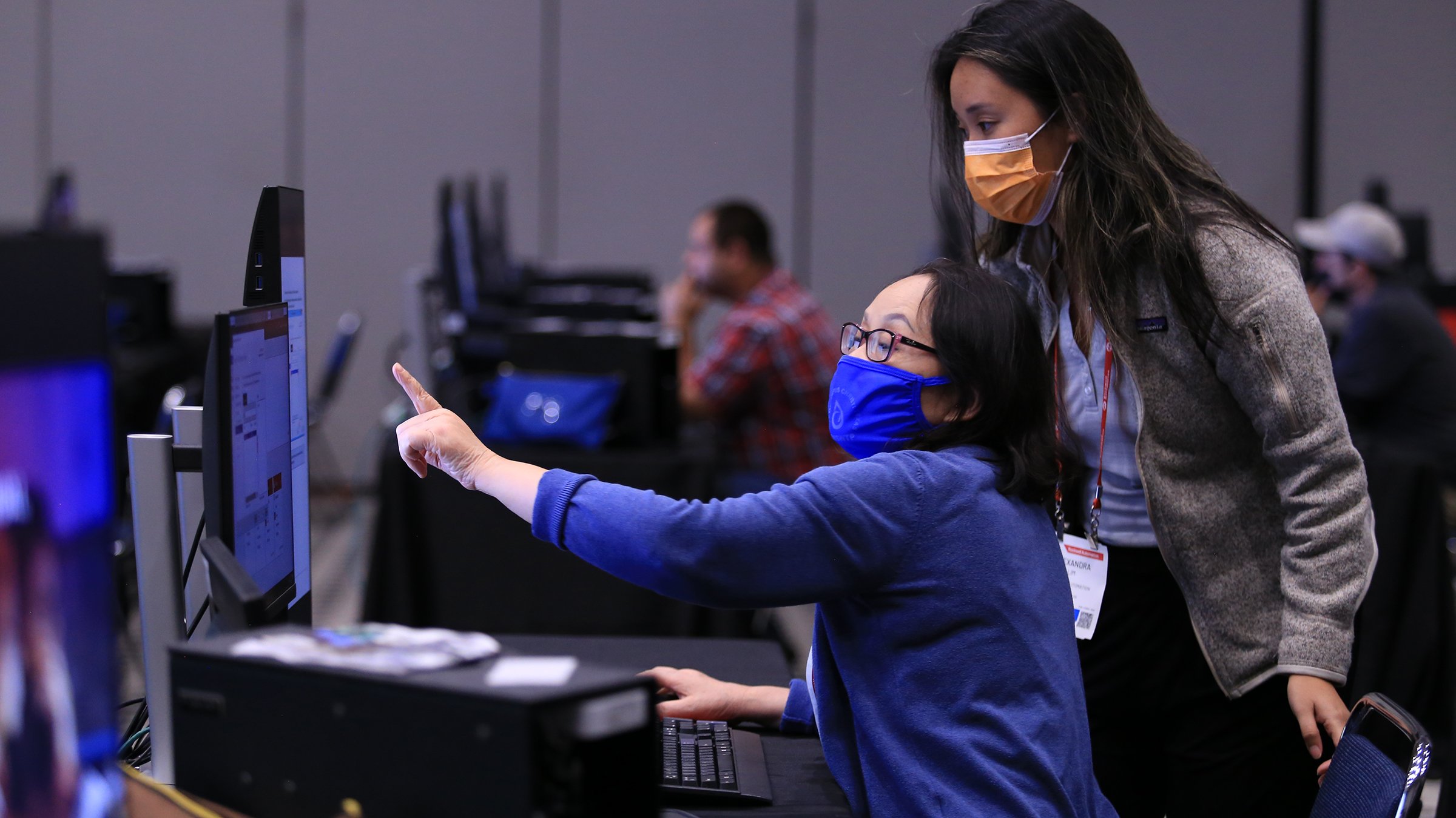 Two people wearing masks in a session looking at a monitor at Automation Fair PSUG