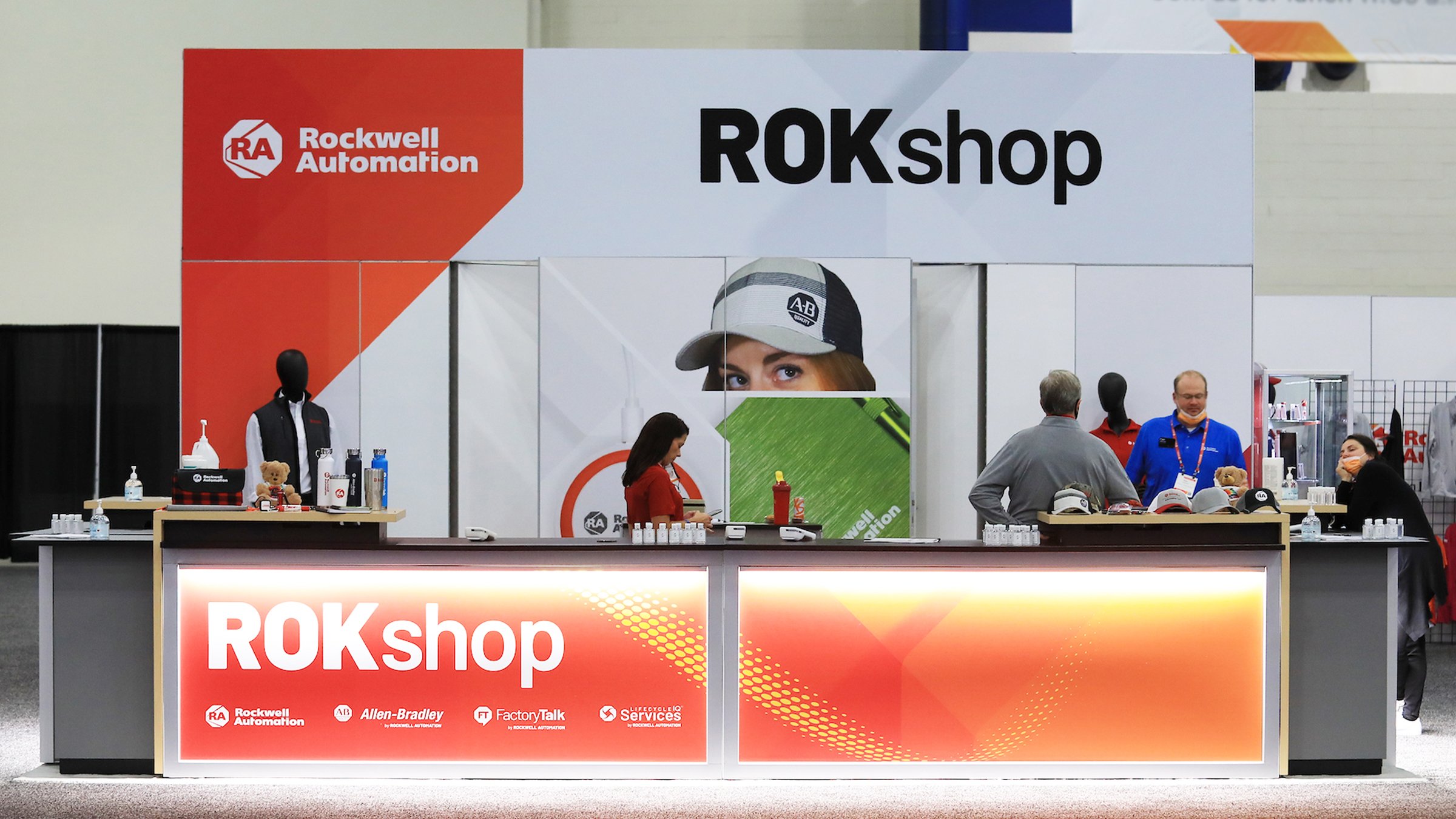 The Rockwell Automation ROKShop store at an event with people standing behind the counters and merchandise in the background.