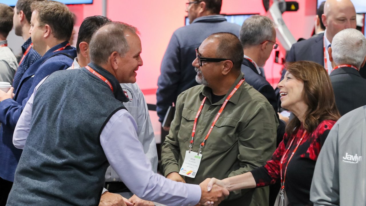 Group of people on the show floor at Automation Fair 2022. Two people in middle are shaking hands and greeting each other.