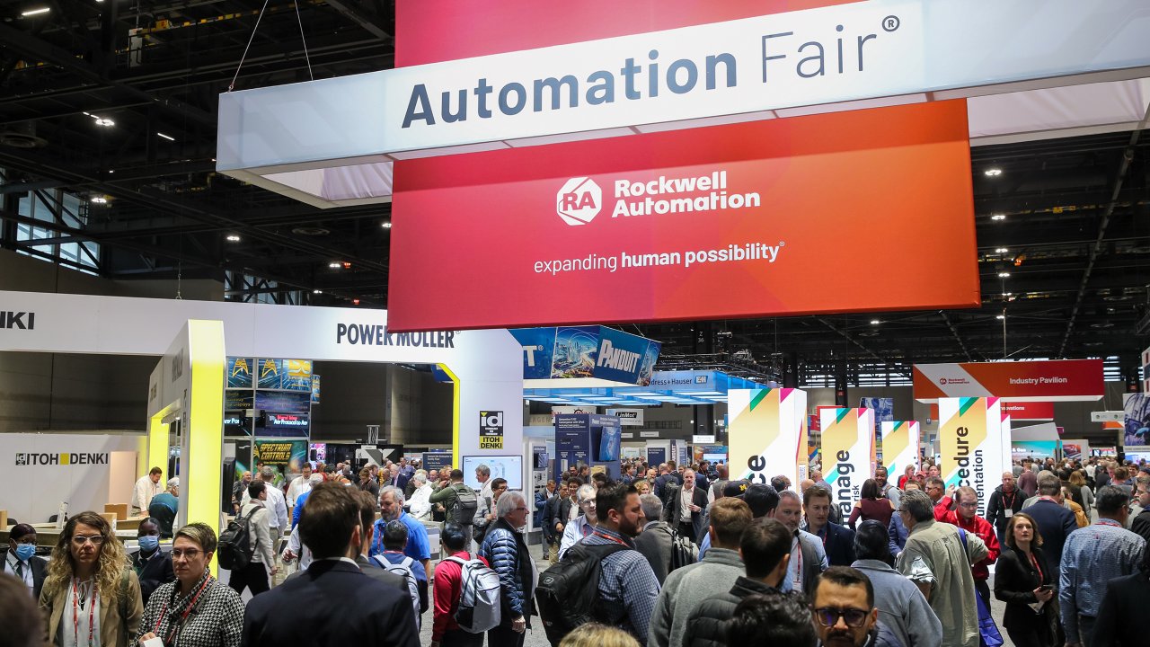 Entrance to Automation Fair 2022, large crowd walks under big hanging sign. Attendee booths are visible.