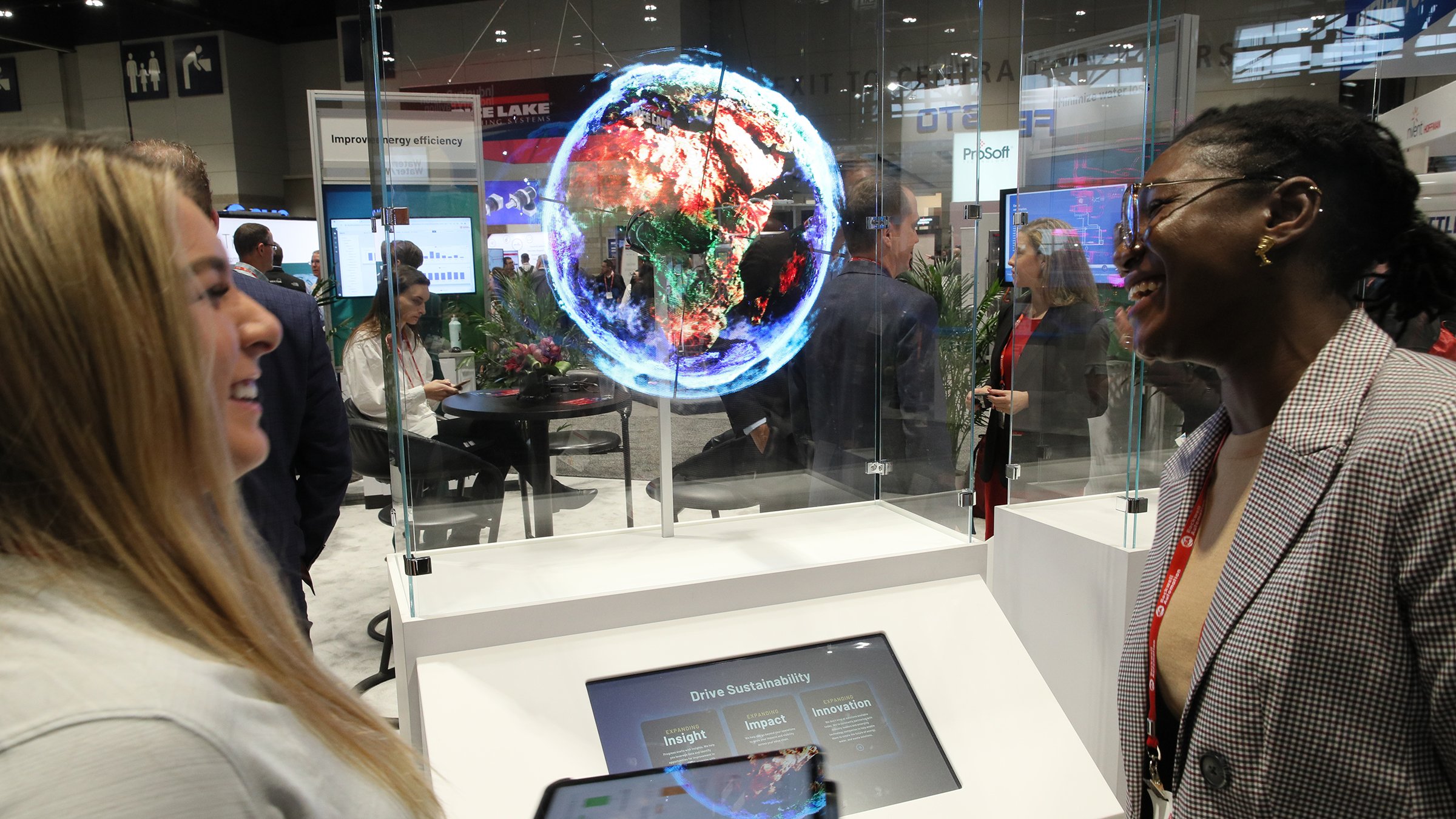 Two women laughing and interacting looking at display of a globe using a tablet