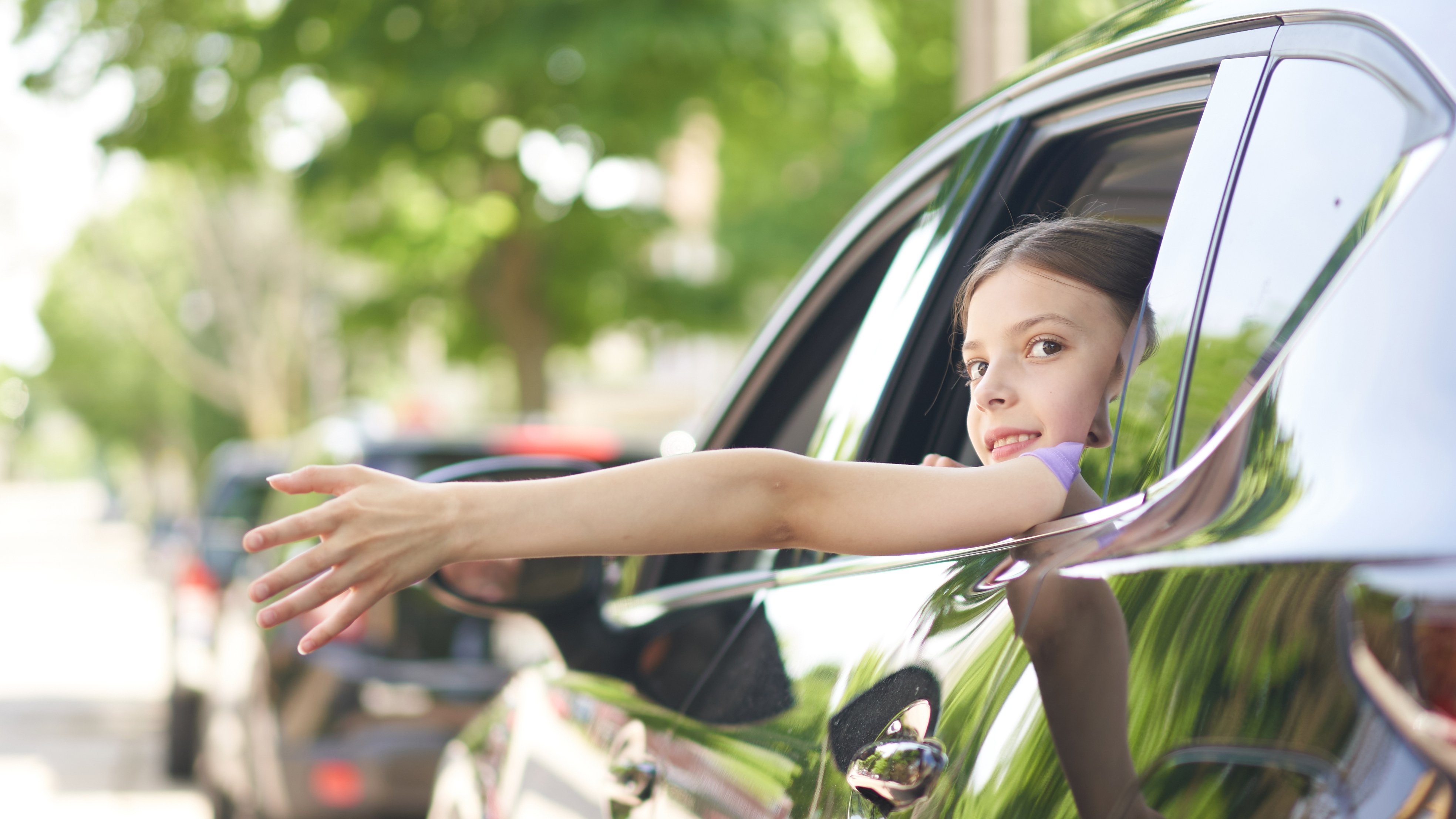 Automotive little girl reaching from the inside of a car
