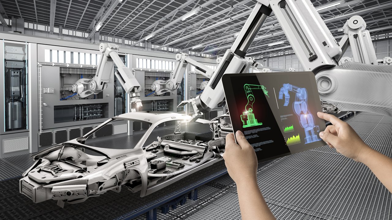 Person operating a robot in a car factory with a tablet