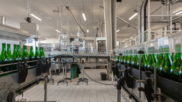 Many green bottles on conveyor belt in a bottling plant