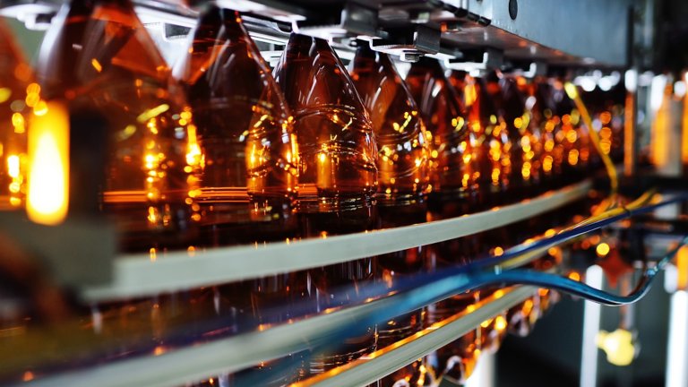 Industrial production of plastic bottles for low-alcohol beverages, soda and sunflower oil. Empty PET bottles of brown color on the background of modern equipment.