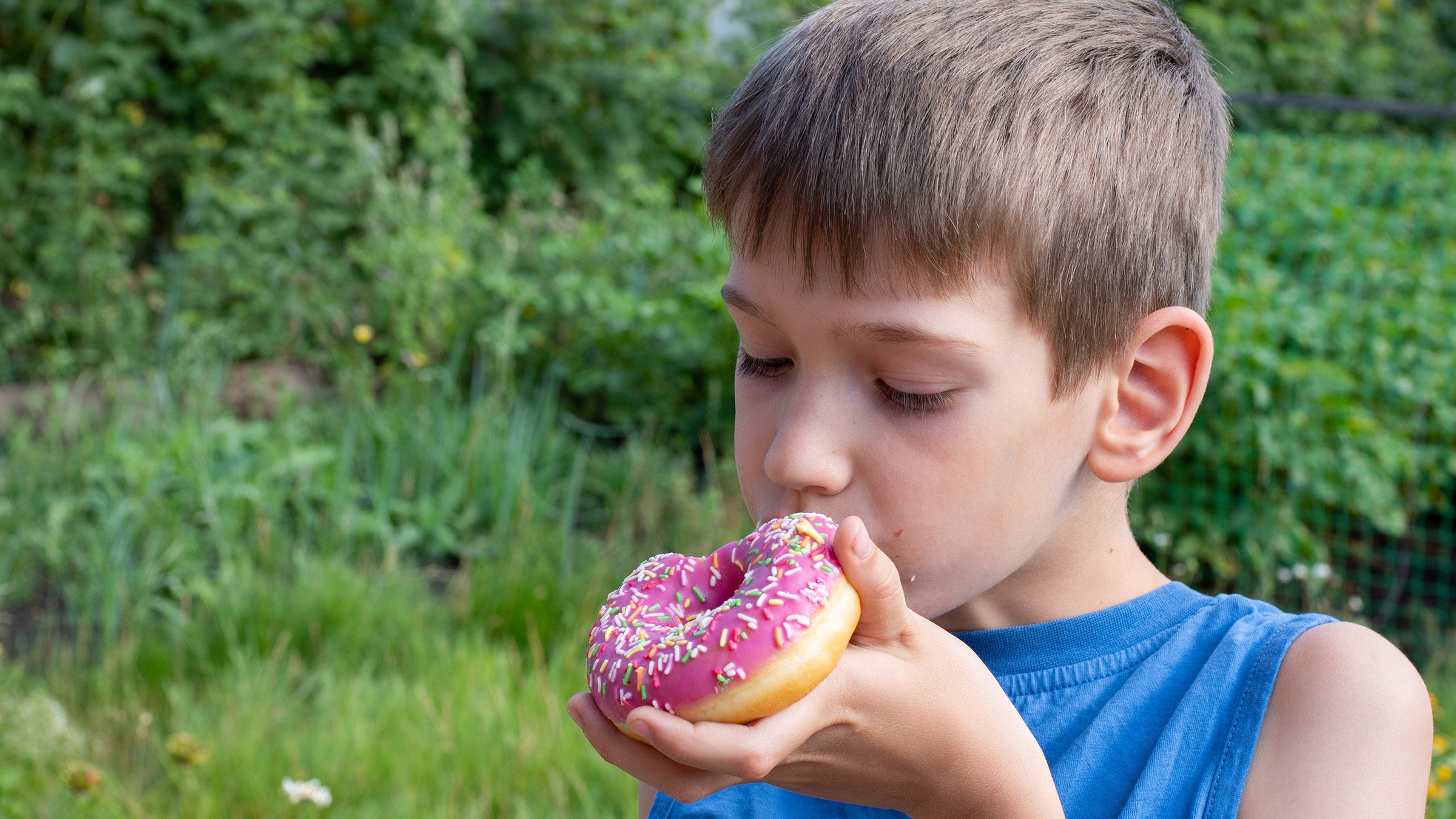 Boy eating sweet baked donut snack