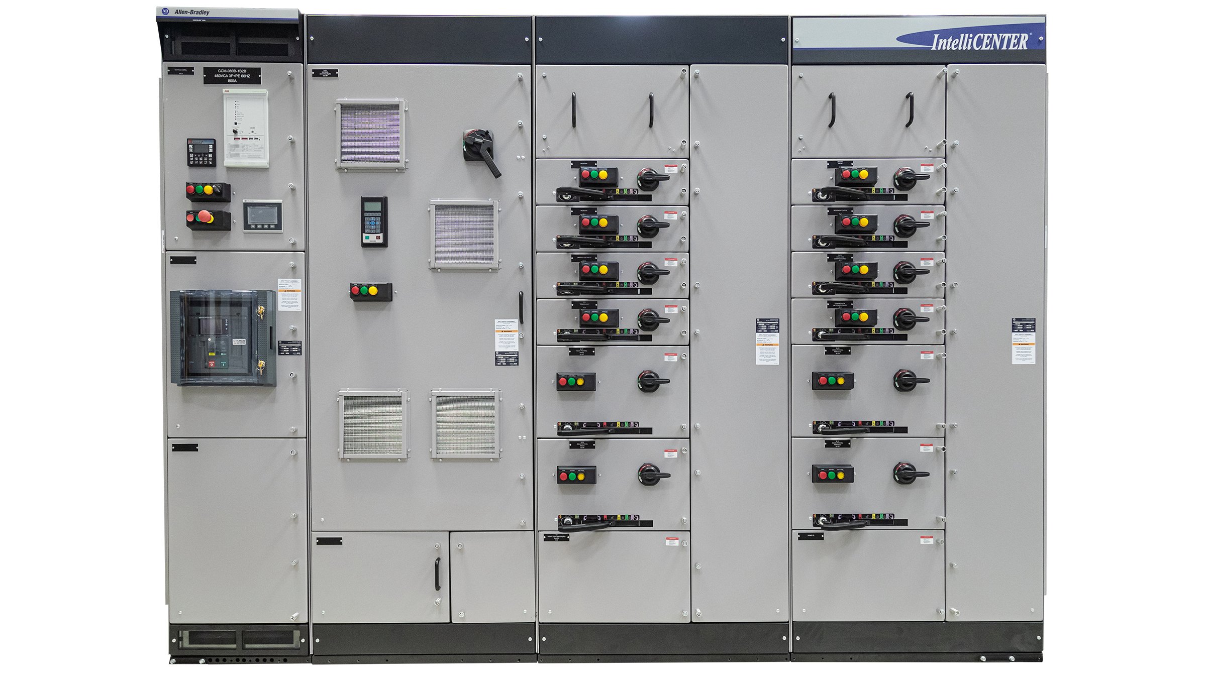 Um gabinete metálico grande e cinza direcionado para os observadores. Dividido por quatro seções verticais, este contêiner industrial tem 18 portas de tamanhos diferentes com puxadores, luzes LED, interruptores, teclados, aberturas e/ou botões multicoloridos.