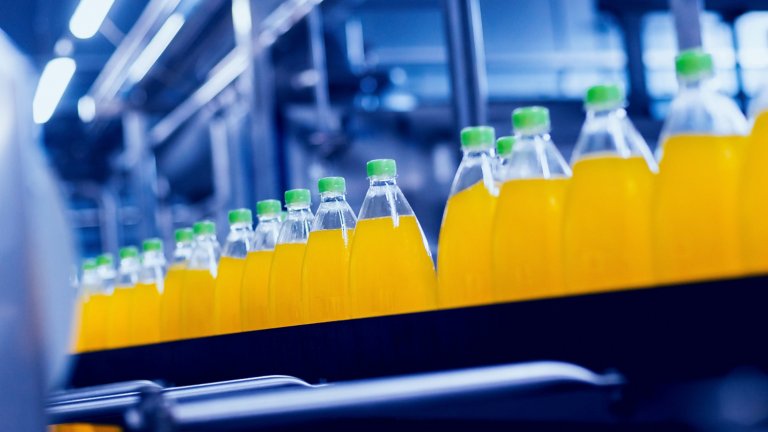 Conveyor belt with juice bottles in beverage manufacturing plant.