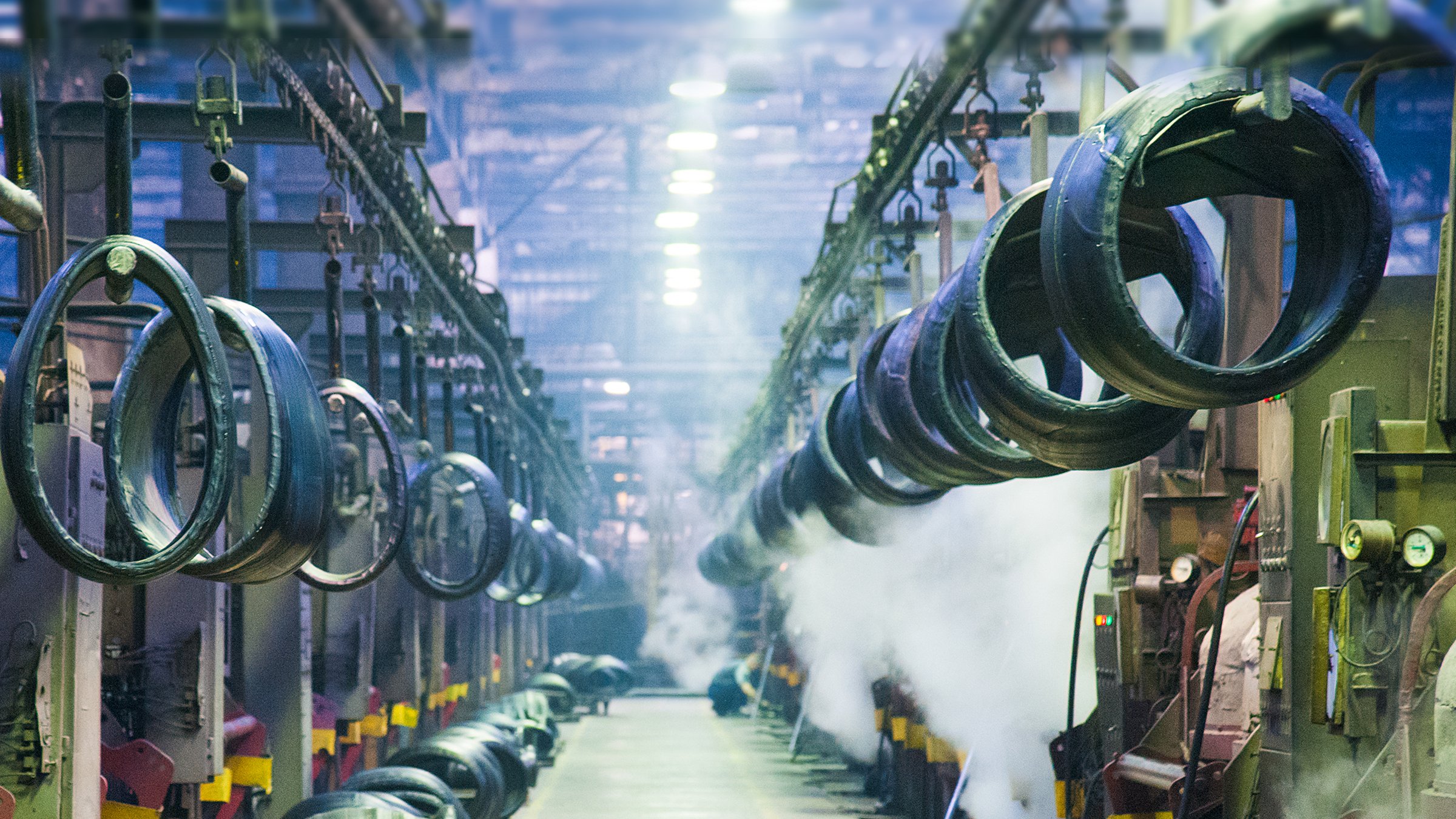 A row of tires being manufactured.ed There is a green backgound with swirls of corrosive gas surrounding the black tires.