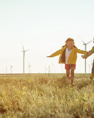 Children running on field with windmills in the back