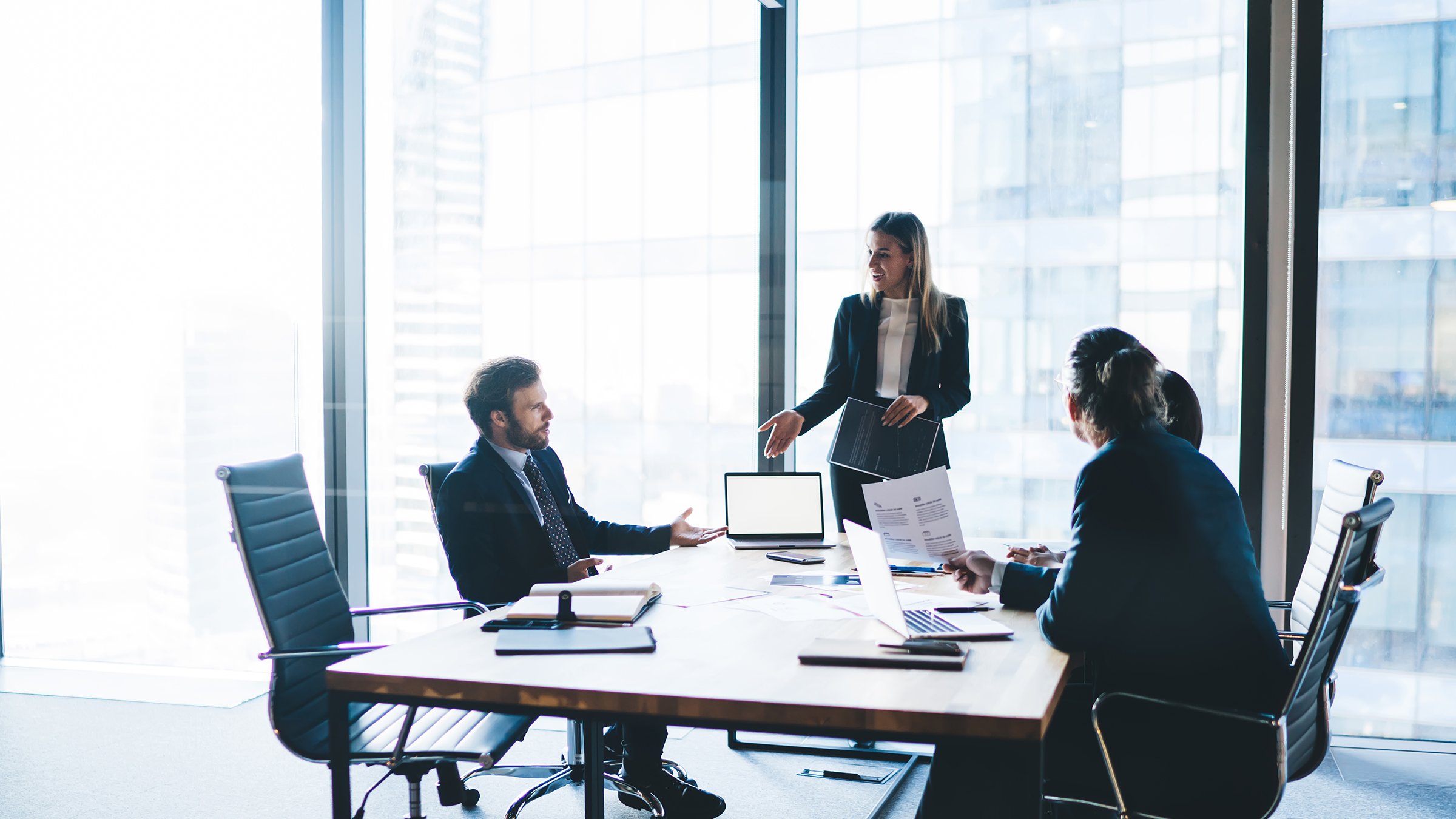 High angle of content female entrepreneur in elegant clothes explaining business strategy to board of directors while standing near table during meeting