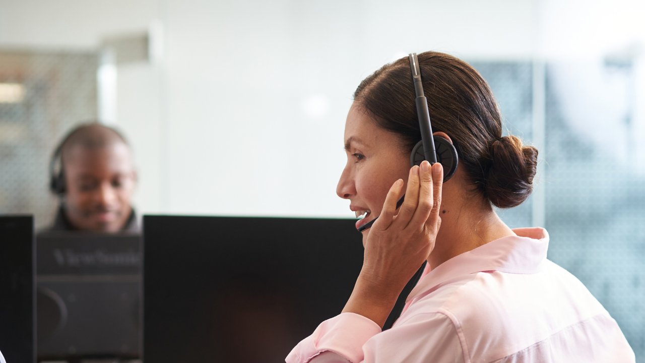 customer care representative speaking into a headset while sitting in front of a computer