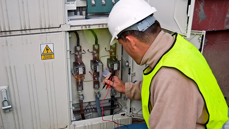 Electrician studying current-voltage switchgear in electrical equipment.