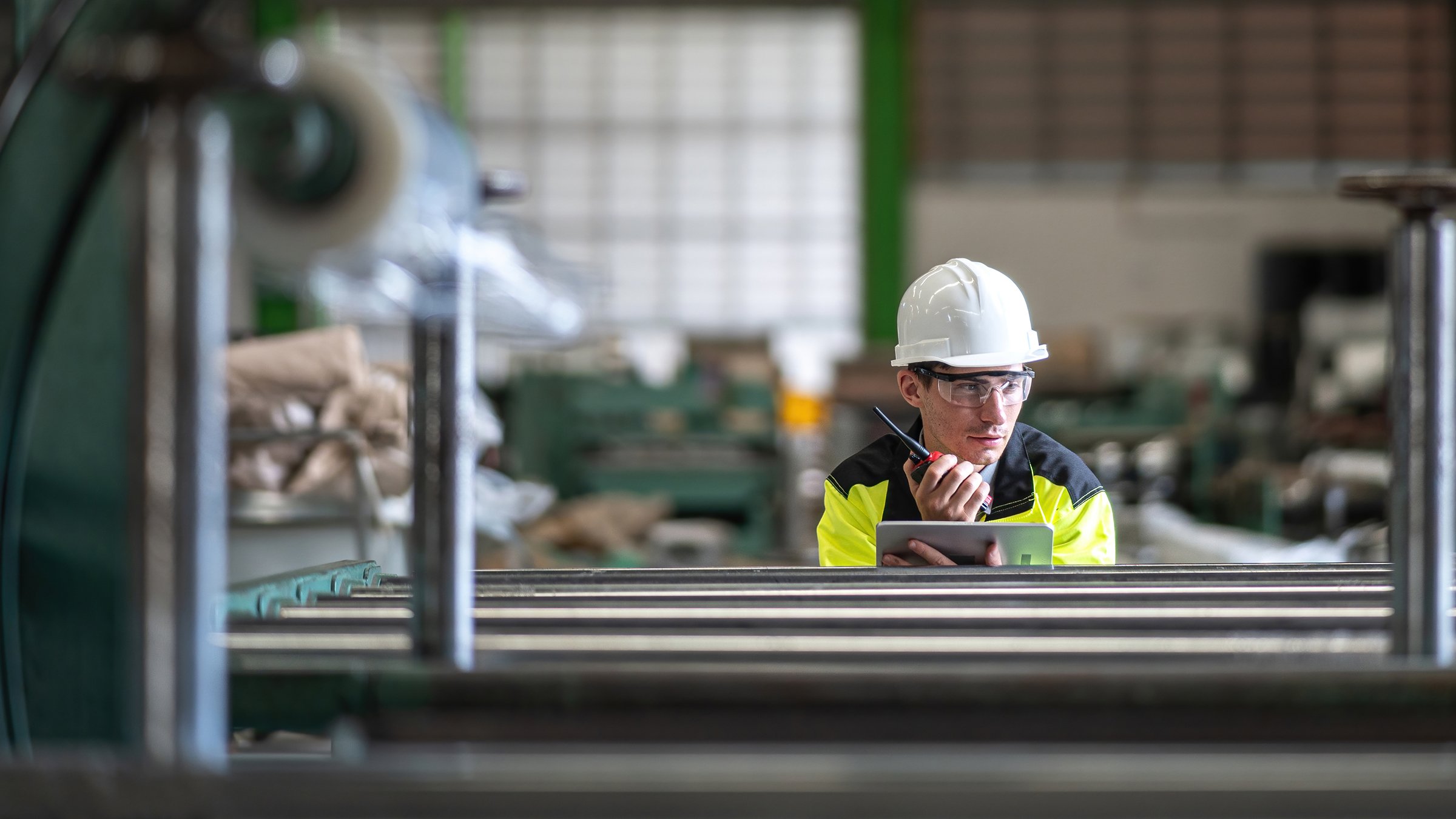 Ingeniero con una tableta trabajando en una fábrica. Primer plano de ingeniero utilizando una máquina de horquilla. Ingeniero con gafas de protección en una fábrica.