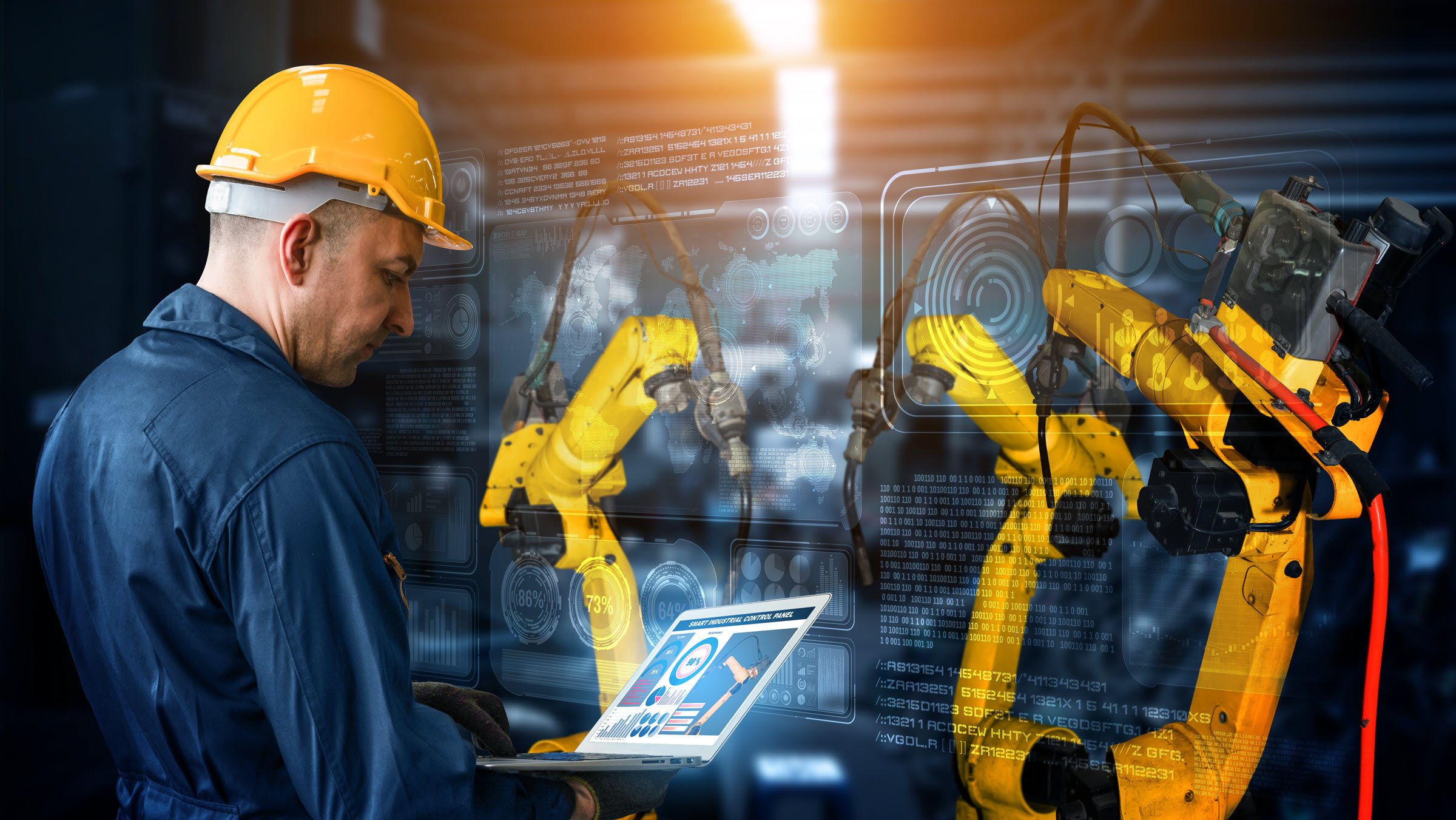 Immagine di un tecnico con un casco giallo che lavora sui bracci automatici di un robot smart nell’ambito della tecnologia di produzione digitale in fabbrica, il che mostra un processo di produzione automatizzato dell’Industry 4.0 o la 4ª rivoluzione industriale, con software IOT per il controllo delle operazioni