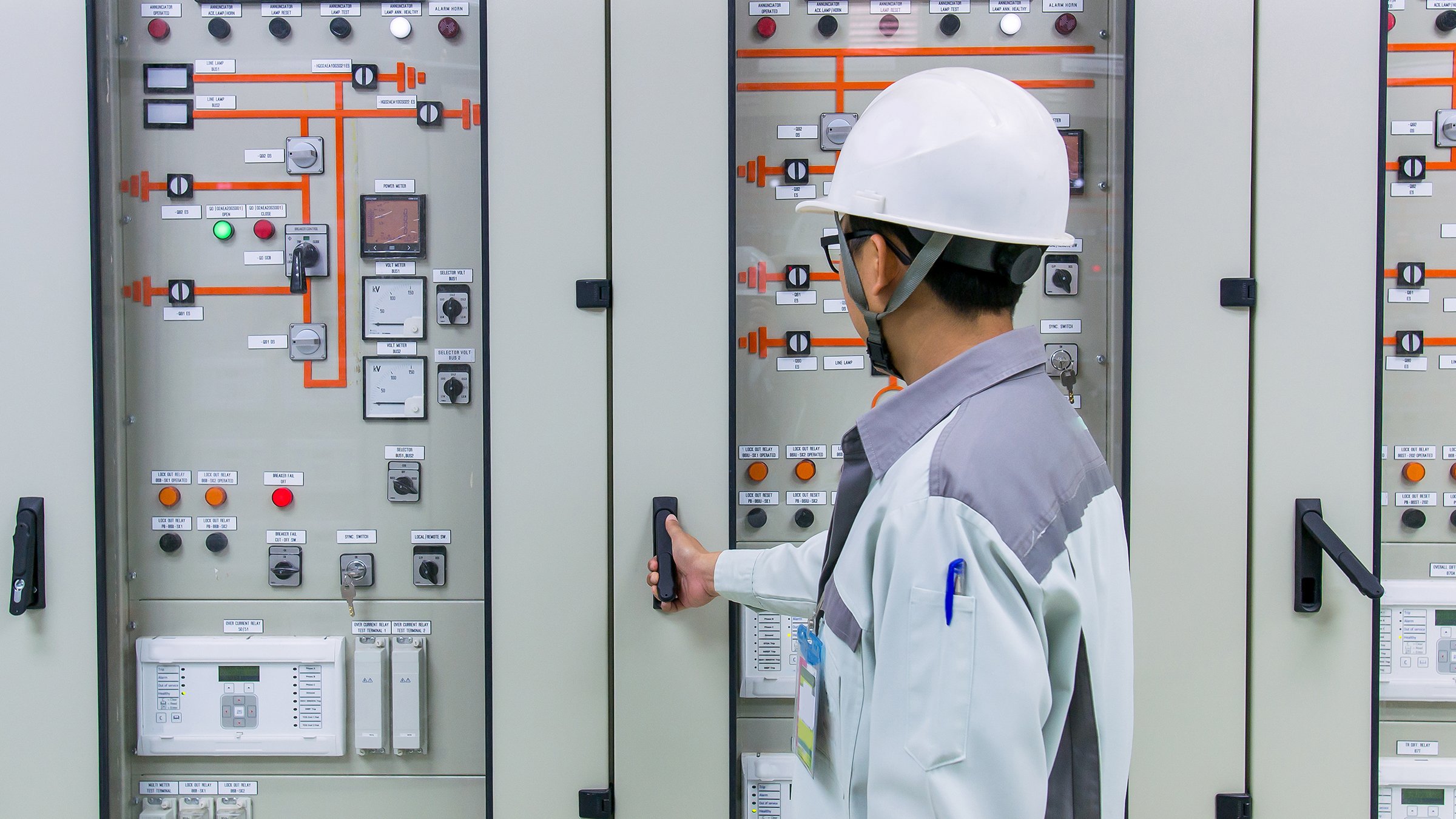Engineer in front of 115kV control protection panel at power plant