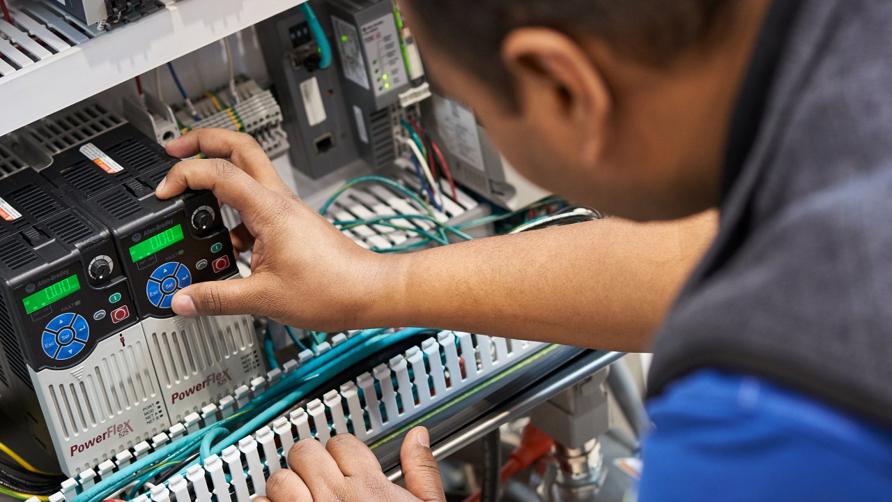 Engineering working in a control cabinet panel containing PowerFlex and other Rockwell Automation products