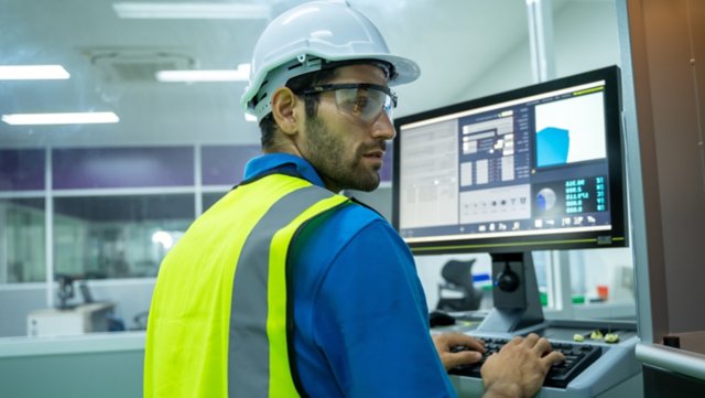 Ingeniero utiliza una computadora portátil para trabajar y verificar una máquina en una gran fábrica industrial