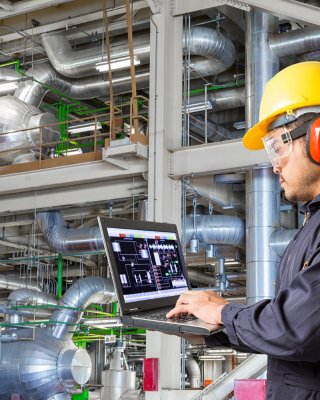 Engineer using laptop computer for maintenance equipment and pipeline system in thermal power plant factory