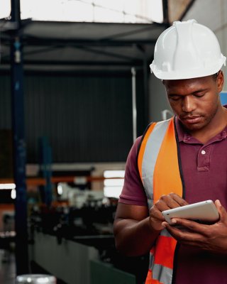 Engineer in white hard hat looking at tablet